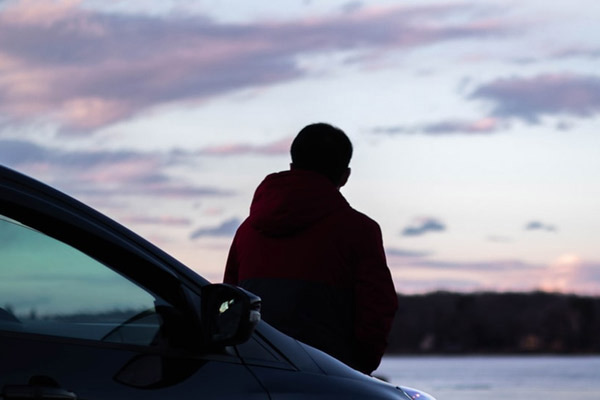 Young man sitting on car - Auto Insurance