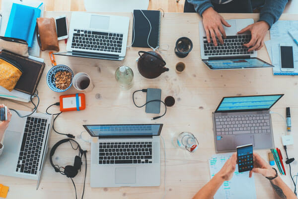 Top view of multiple laptops and working hands - Commercial Insurance