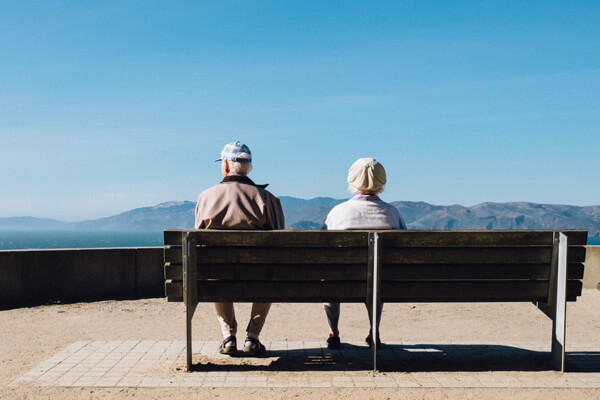 Elderly couple sitting on bench - Life Insurance